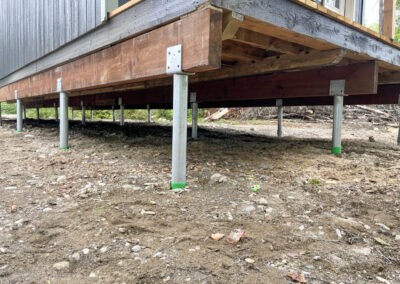 A close-up view of a raised building foundation supported by galvanized steel Techno Metal Posts anchored into the ground.